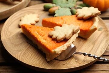 Slices of delicious homemade pumpkin pie on wooden plate, closeup