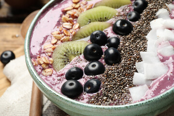 Delicious acai smoothie with fruits and chia seeds in bowl, closeup