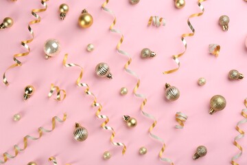 Shiny serpentine streamers and Christmas balls on pink background, flat lay