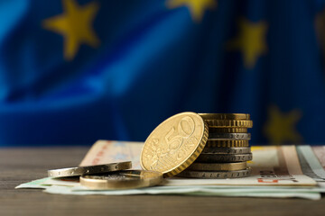 Coins and banknotes on wooden table against European Union flag, space for text © New Africa