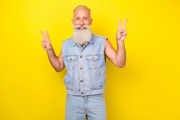 Naklejka premium Photo of funky cool retired guy wear jeans waistcoat smiling showing two v-signs isolated yellow color background