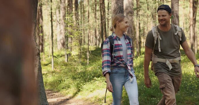 young couple ⁬with backpacks on a walk in forest. backpacking trip, summer adventure hike