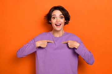 Photo of excited funny girl dressed purple pullover pointing fingers herself isolated orange color...