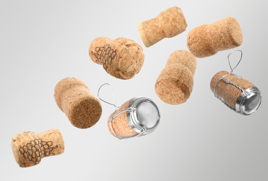 Many corks of sparkling wine bottles falling on light grey background - Powered by Adobe
