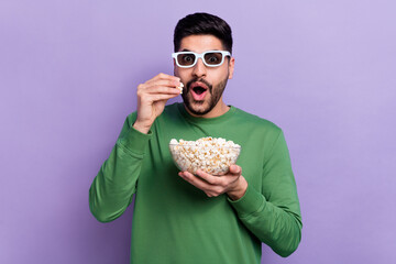 Photo of young impressed astonished man dressed green pullover watching cool excited movie eat...