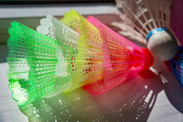 Several colorful shuttlecocks on a windowsill indoor at sunny day