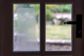 Condensation caused by gas leak inside a double glazed pane of glass due to gas leak on a wooden outside door.