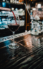 bartender pouring red wine into a glass in cafe or bar on the bar counter