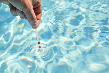 Checking the water quality of a pool with the help of a test strip with PH value, chlorine and...