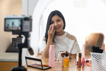 Young beautiful Asian woman and professional beauty make up artist vlogger or blogger recording makeup tutorial to share on website or social media. Business online influencer on social media concept.