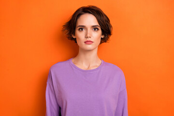 Photo of serious confident young lady wear violet sweatshirt isolated orange color background
