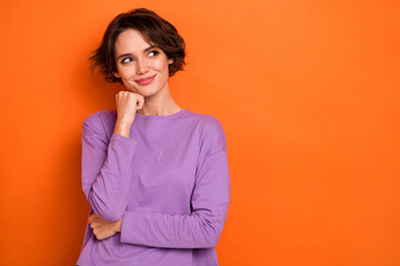 Portrait of pretty lady hand touch chin look interested empty space wonder isolated on orange color background