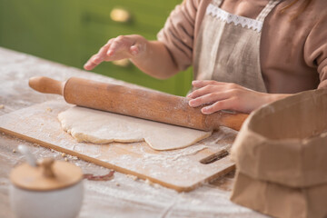 At luminous amazing rustic kitchen a cute girl preparing her favourite dessert she using the kitchen roller for dough and take some flour add over the dough at the kitchen island