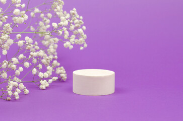 Cosmetic beauty showcase. White round podium for advertising cosmetic products on a purple background with gypsophila bouquets. Empty stand for packing.