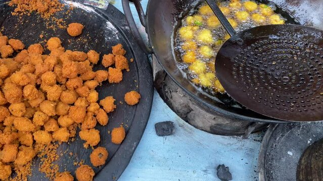 Top shot of a local cooking potato pakora on a roadside food stall at daytime.