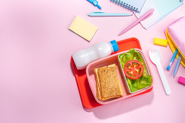 Healthy school meal, back to school concept. Children packed lunch box with balanced diet snack food - yogurt, cereal toast sandwich, apple, fresh vegetable salad, high-colored bright background