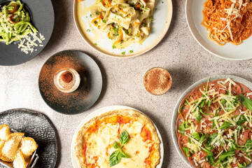 Top view of various Italian food dishes including desserts on a concrete background. Pizza, Carpaccio, Spaghetti, Ragu, Tiramisu. High quality photo