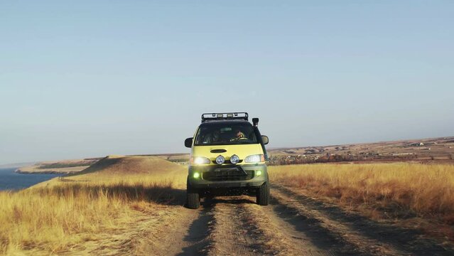 A yellow campers van rides off-road in summer morning