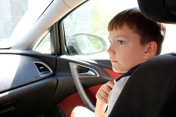 The boy is sitting in the front seat of the car. Close-up portrait.