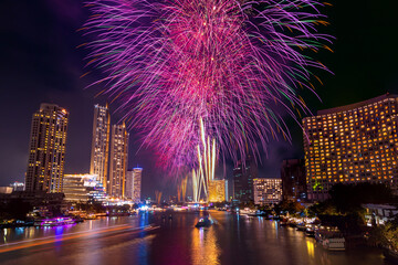 Colorful Firework at river with cityscape night light view of Bangkok skyline at twilight time..New Year celebration fireworks, Thailand.Fireworks light up to sky at Christmas and New Year festival