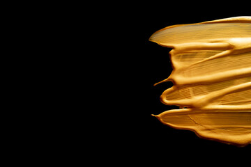 golden smear oil paint spot isolated on black background