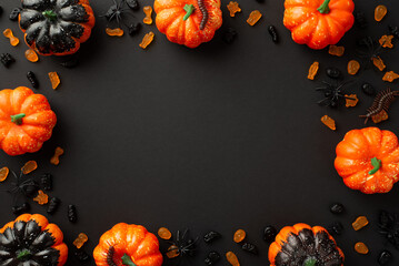 Halloween creepy decor concept. Top view photo of pumpkins jelly candies centipedes and spiders on isolated black background with copyspace in the middle