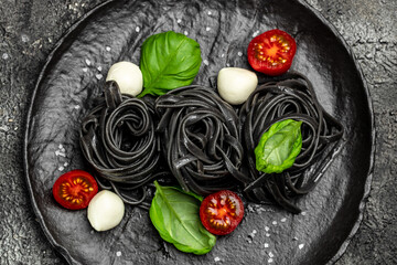 black pasta with cuttlefish ink and green basil leaves. Pasta of durum wheat semolina with squid...