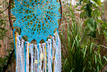 Dream catchers crocheted from threads on a wooden base in the colors of the Ukrainian flag, namely in yellow and blue, decorated with lace, threads, feathers and wooden beads on the street