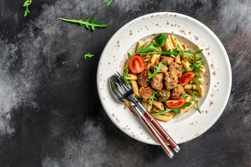 penne pasta with meatballs and spicy tomato sauce on a dark background. Restaurant menu, dieting, cookbook recipe banner, place for text, top view
