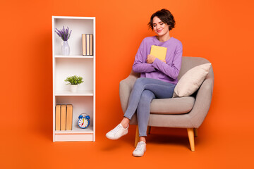 Full length portrait of pretty nice lady sitting chair hold cuddle book closed eyes isolated on orange color background
