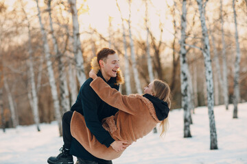 Loving young couple hugging and having fun in winter forest park.