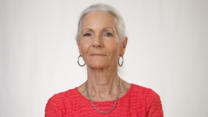 Close up portrait of pretty caucasian elderly woman on white background, looking at camera smiling.