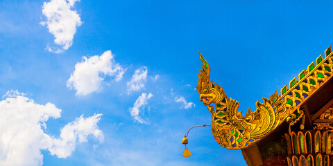 Fototapeta na wymiar Beautiful golden naga and buddhist bells hanging on art roof of buddhist temple,Gable of the Thai Northern art style, Buddhist temple with blue sky in Temple at Chiang Mai Northern Thailand.