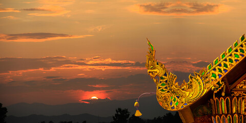 Beautiful golden naga and buddhist bells hanging on art roof of buddhist temple,Gable of the Thai Northern art style, Buddhist temple with sunset. in Temple at Chiang Mai  © cmmedia99
