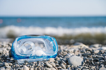 Close-up of mask for snorkeling on a pebble beach next to the sea. Summer vacation.