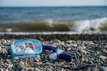 Close-up of mask for snorkeling on a pebble beach next to the sea. Summer vacation.