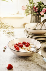 Breakfast porridge bowl with raspberries on table at window background