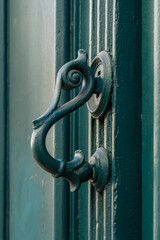 Closeup view of vintage brass door handle in shape of stylized bird head isolated on ancient green wooden door, Montpellier, France	
