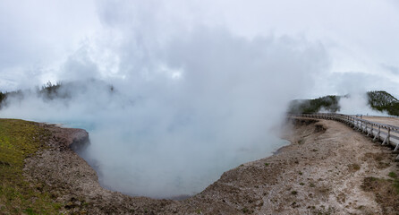 Hot spring Geyser with colorful water in American Landscape. Cloudy Sky. Yellowstone National Park, Wyoming, United States. Nature Background Panorama