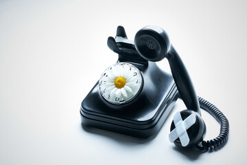 High angle view black bakelite telephone with strips on the speaker and a daisy on the dial with...