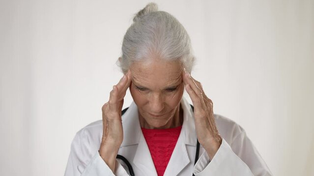 Portrait of exhausted woman doctor rubbing forehead and look at camera, tired girl doctor feels headache from working hard.