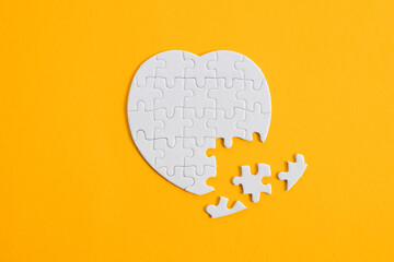 Puzzle heart with one missing piece on yellow, health care concept - Powered by Adobe