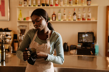 Young beautiful calm african woman in apron rubbing glass