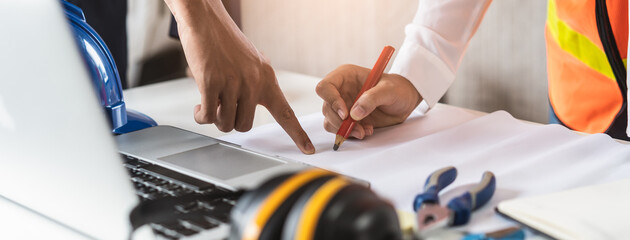 Close up hands of businessman from consultancy service discussing with project contractor and reviewing blueprint for build real estate facilities.