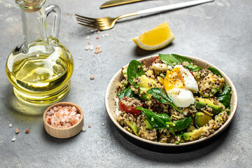 Quinoa buddha bowl with avocado, egg, tomatoes, spinach and sunflower seeds on a dark background. Homemade food. Healthy, clean eating. Vegan or gluten free diet, place for text, top view