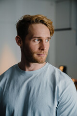 Fototapeta premium Young bearded man wearing t-shirt smiling and looking aside at home