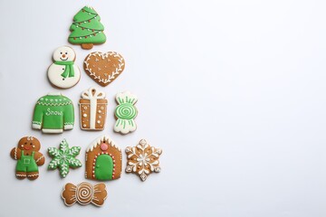 Christmas tree shape made of delicious gingerbread cookies on white background, flat lay. Space for...