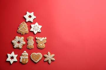 Delicious gingerbread cookies arranged in shape of Christmas tree on red background, flat lay....