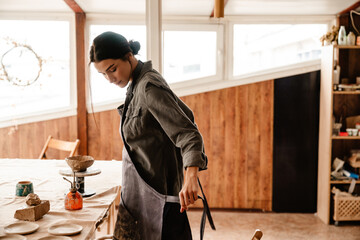 Young beautiful woman potter tying an apron