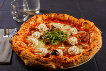 Pizza napoletana con pomodoro, mozzarella. rucola fresca r ciuffi di ricotta servita in una pizzeria napoletana